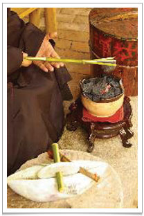 A piece of tea cake being toasted on a open fire;- can you imagine the fragrance that permeates the air! At the bottom of the picture is a stone Nian for grinding the tea.